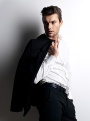 Fototapeta premium Fashion young man in white shirt holds the black jacket