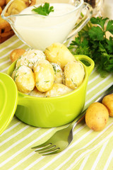 Tender young potatoes with sour cream and herbs in pan
