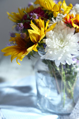 Bouquet of wild flowers in glass vase on napkin close-up