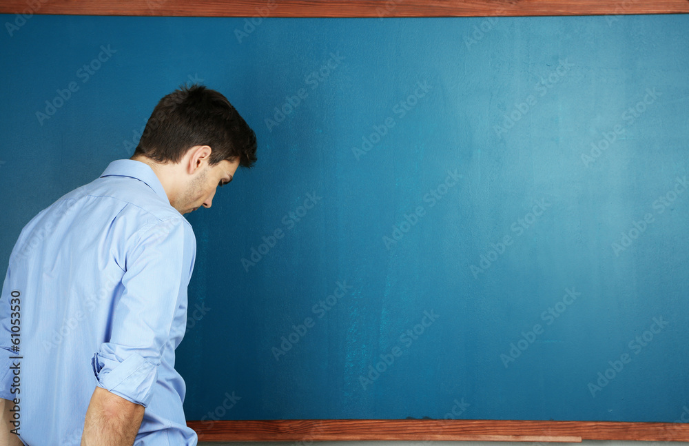 Wall mural young teacher near chalkboard in school classroom