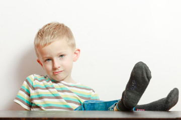 Naklejka premium Manners. Bored boy child kid with feet on the table. At home.