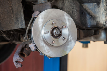 Fototapeta premium Front disk brake on car in process of damaged tyre replacement.