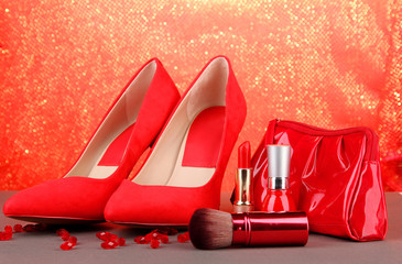 Beautiful red female shoes and cosmetics, on bright background
