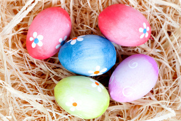 Easter eggs decorated with daisies on a nest of straw