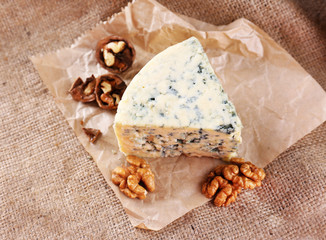 Tasty blue cheese with nuts, on burlap background