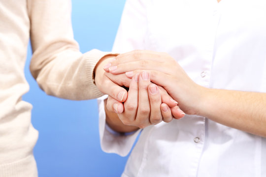 Medical doctor holding hand of patient, on light background
