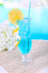 Glass of cocktail on table on light blue background