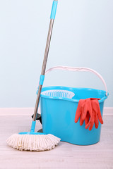 Floor mop and bucket for washing in room on blue wall