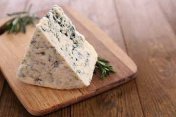 Tasty blue cheese with rosemary, on wooden table