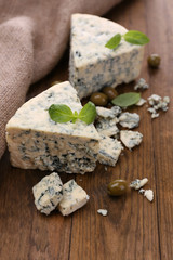 Tasty blue cheese with olives and basil, on wooden table