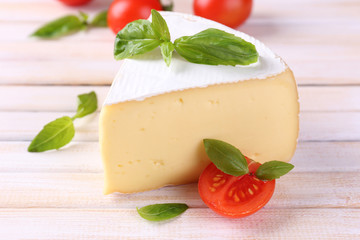 Tasty Camembert cheese with basil and tomatoes, on wooden table