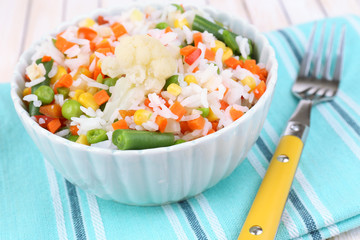 Cooked rice with vegetables on wooden table close up