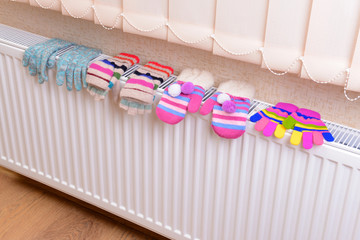 Knitted gloves drying on heating radiator