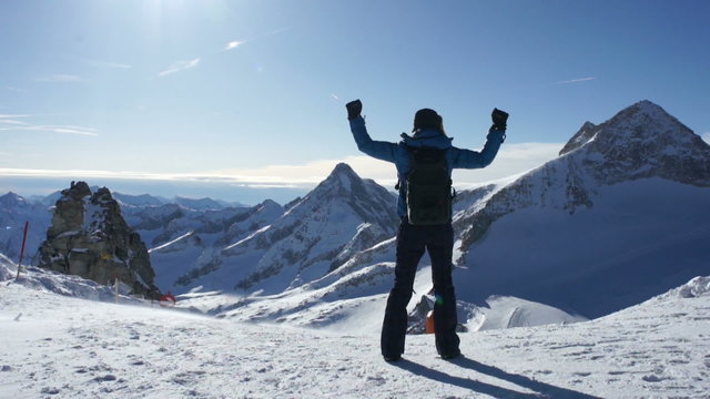 Woman standing on mountain peak with arms outstretched