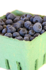 Blueberries in a green basket, isolated on white.