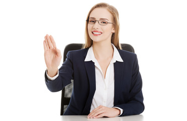 Beautiful business woman is sitting and showing stop gesture.