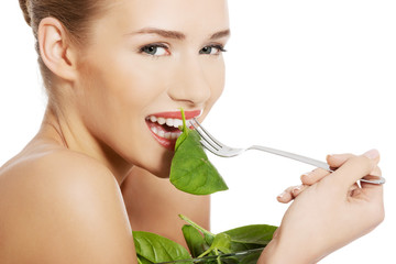Beautiful caucasian topless woman eating lettuce from a bowl wit