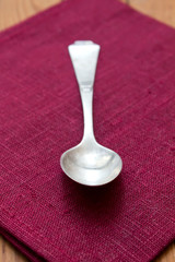 Vintage silver spoon on napkin on wooden background.