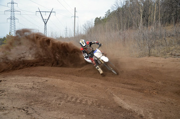 Motocross racer moves along sandy parapet turning track