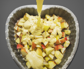 Pouring batter on apples in baking dish , isolated
