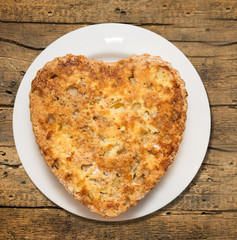 Sponge cake in heart shaped with apples on old wooden table
