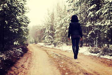 Woman is walking through forest in wintertime