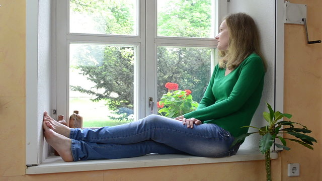 wife sit on sill and watch through window waiting for husband
