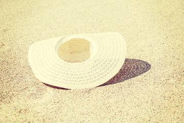 Fototapeta na wymiar Droped straw summer hat on bright sand.