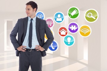 Composite image of smiling businessman with hands on hips