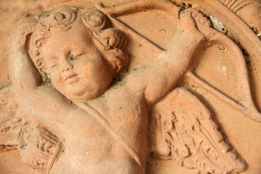 antique relief of cupid  with arrow and bow in tuscan terracotta