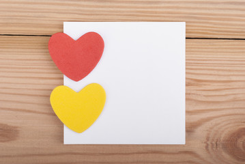 Two hearts and paper on wooden background.