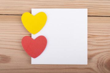 Two hearts and paper on wooden background.