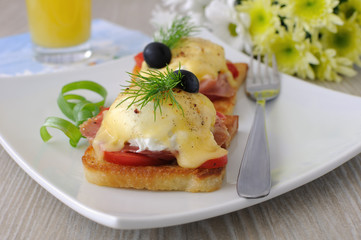Eggs Benedict with ham and tomato on toast with cheese