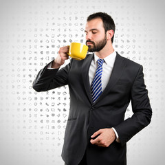 Young businessman drinking a coffee over background with icons
