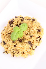 Risotto with mushrooms on a plate decorated with basil