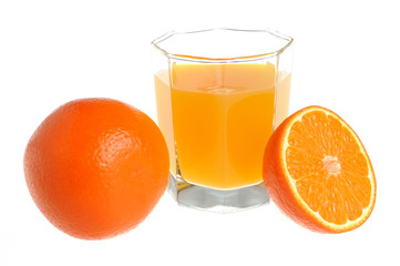 A half and a whole orange with a glass filled with citrus juice