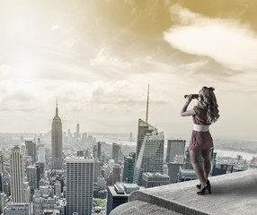 Pin-up woman watching New York City trough binoculars.