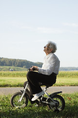 Happy senior woman riding bicycle for toddlers.