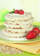 Tasty crispbread with berries on plate, on green table