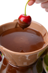 Chocolate fondue with sliced fruits, isolated on white