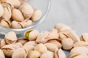 Pistachio nuts in glass bowl on wooden background