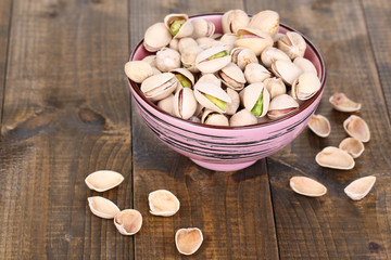Pistachio nuts in bowl on wooden background © Africa Studio