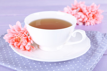 Pink chrysanthemums and cup of tea on wooden table