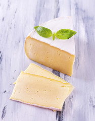 Tasty Camembert cheese with basil, on wooden table