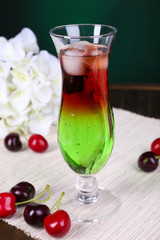 Glass of cocktail on table on dark green background