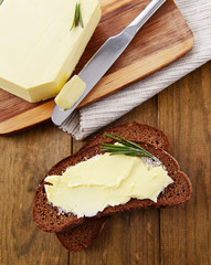Slice of rye bread with butter on wooden table