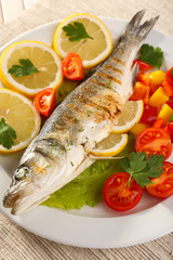 Delicious grilled fish on plate on table close-up