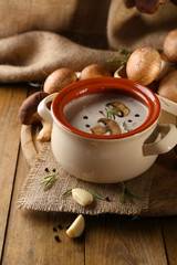 Obraz na płótnie Canvas Mushroom soup in pot, on wooden table, on sackcloth background