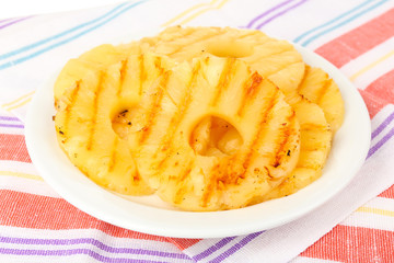 Juicy grilled pineapple on plate on table close-up