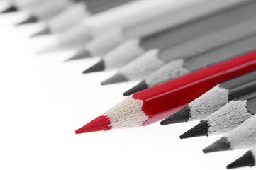 One red pencil standing out from grey pencils. Leadership